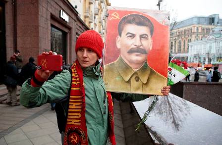 Pemuda komunis Rusia sedang memegang poster Stalin ketika peingati 100 tahun Revolusi Oktober [Foto: Istimewa]
