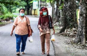 Ilustrasi: Dua orang perempuan berjalan di sebuah Jalan di Medan, Sumatera Utara dengan menggunakan masker wajah