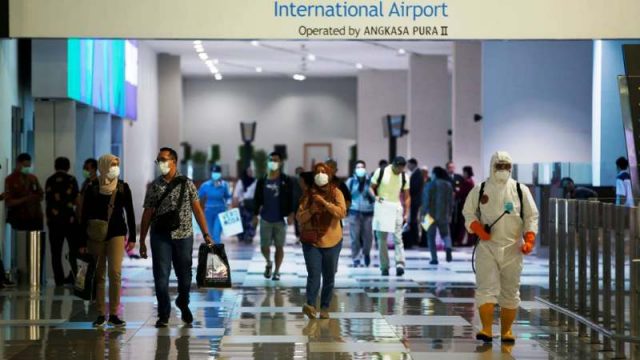 Para penumpang yang mengenakan masker tiba di bandara