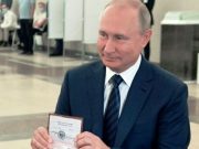 Presiden Rusia Vladimir Putin menunjukkan paspornya kepada petugas pemungutan suara saat tiba di tempat pemungutan suara di Moskow, Rusia, 1 Juli 2020
