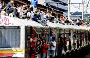 Penumpang kereta bergelantungan di pintu dan atap gerbong (Sumber: tempo.co, 2011)