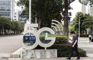 Warga menggunakan smartphone berjalan melewati papan Taman 5G di markas Huawei Technologies Co. di Shenzhen, China - Bloomberg