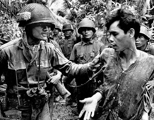 Seorang tersangka anggota Vietcong (kanan) ditangkap oleh tentara ARNV pada tahun 1965 selama Perang Vietnam. (Sumber: alphahistory.com)