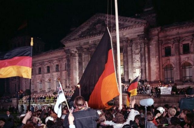 Massa mengibarkan bendera untuk merayakan Reunifikasi Jerman pada tanggal 3 Oktober 1990. (Sumber: Wikimedia Commons)